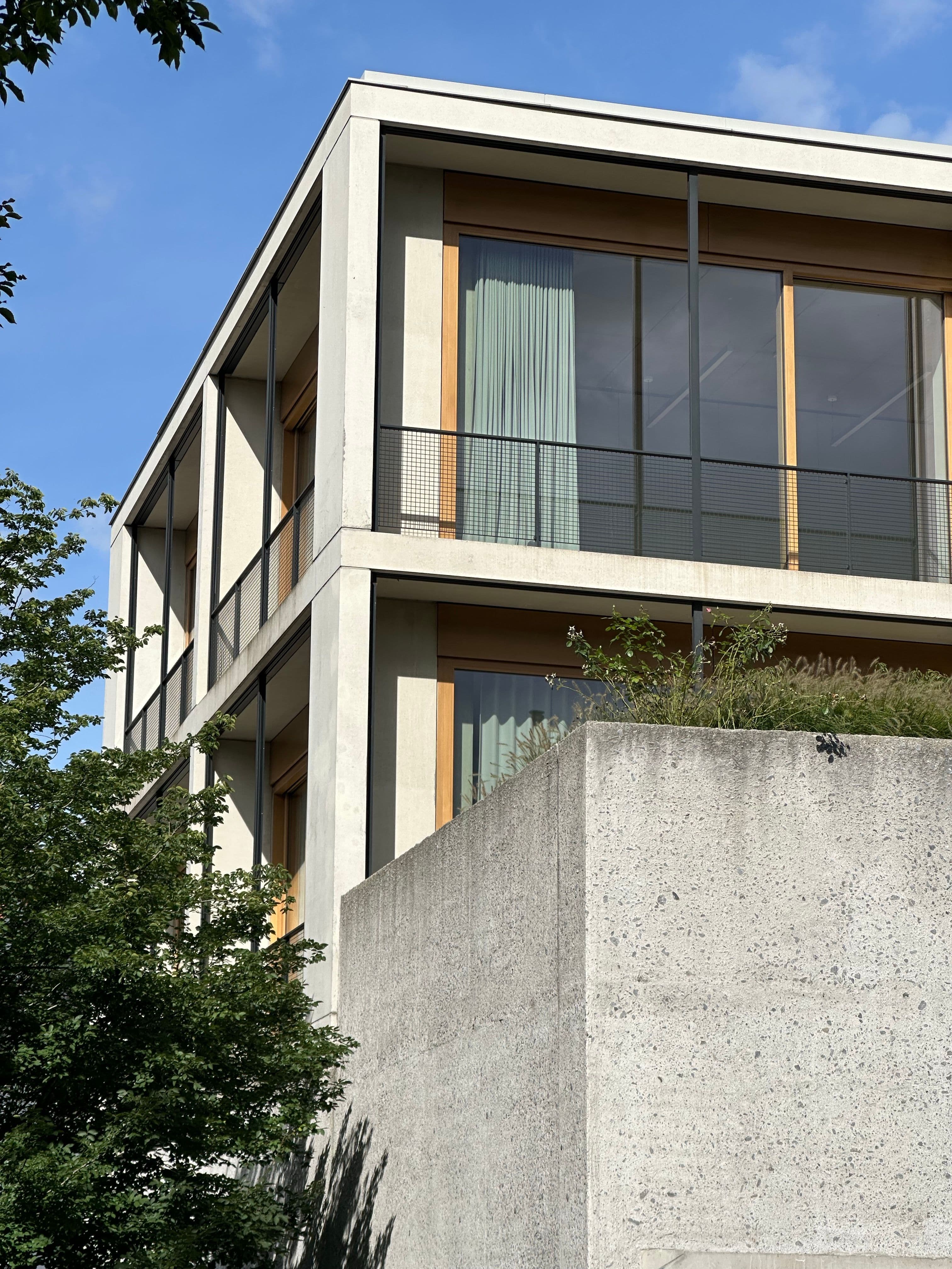 Cam yüzeyler ile brüt beton cepheyi birleştiren modern ticari yapı